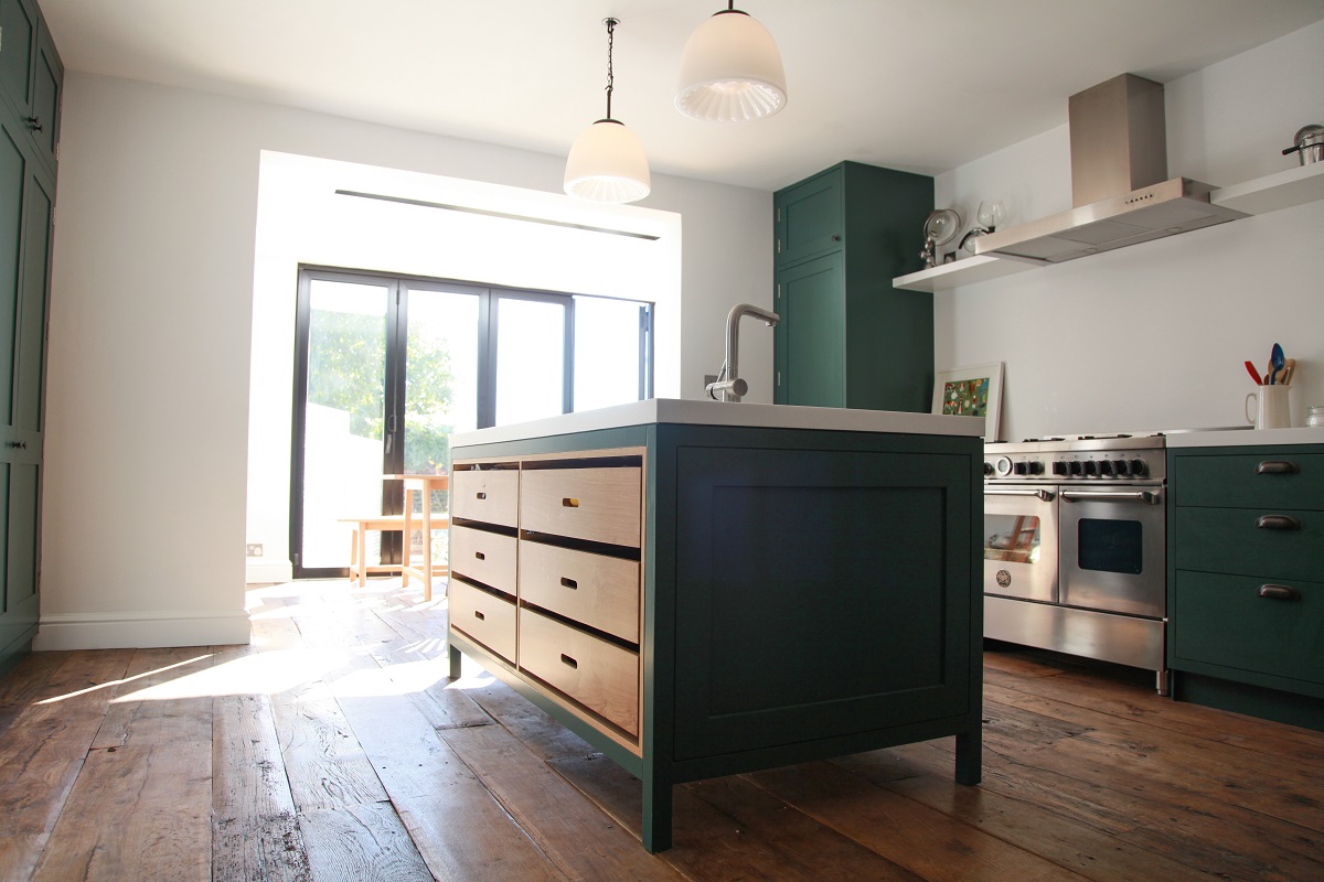 Green cabinets with silver range cooker and white walls