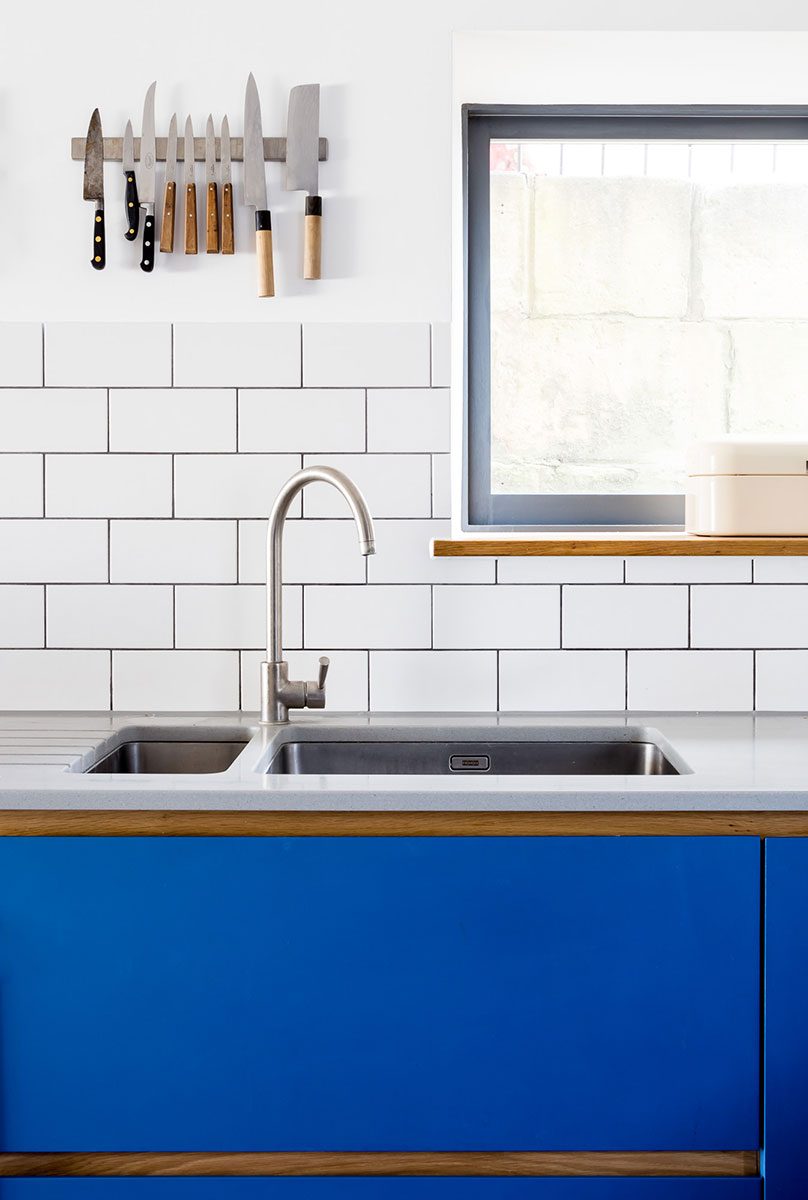 Electric blue kitchen with Corian worktop and white tiles