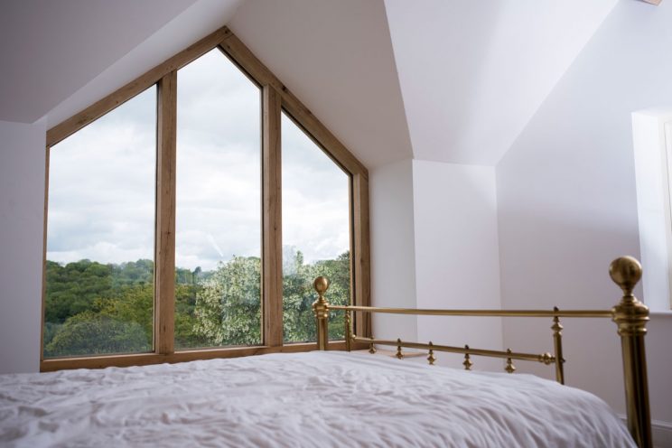 Gable end oak window in master bedroom with brass bed post