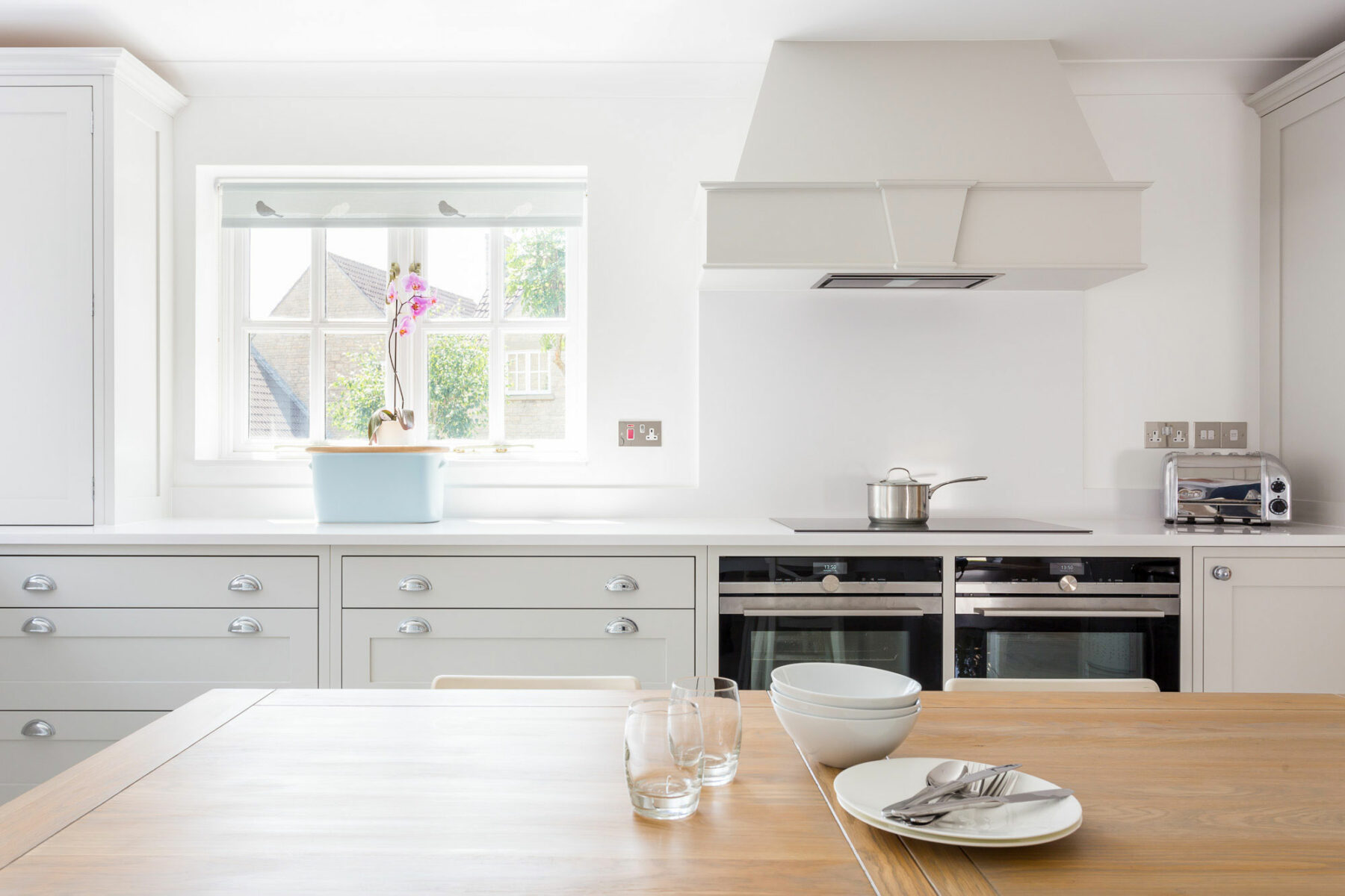 Contemporary white Shaker kitchen in Bath with bespoke cooker hood